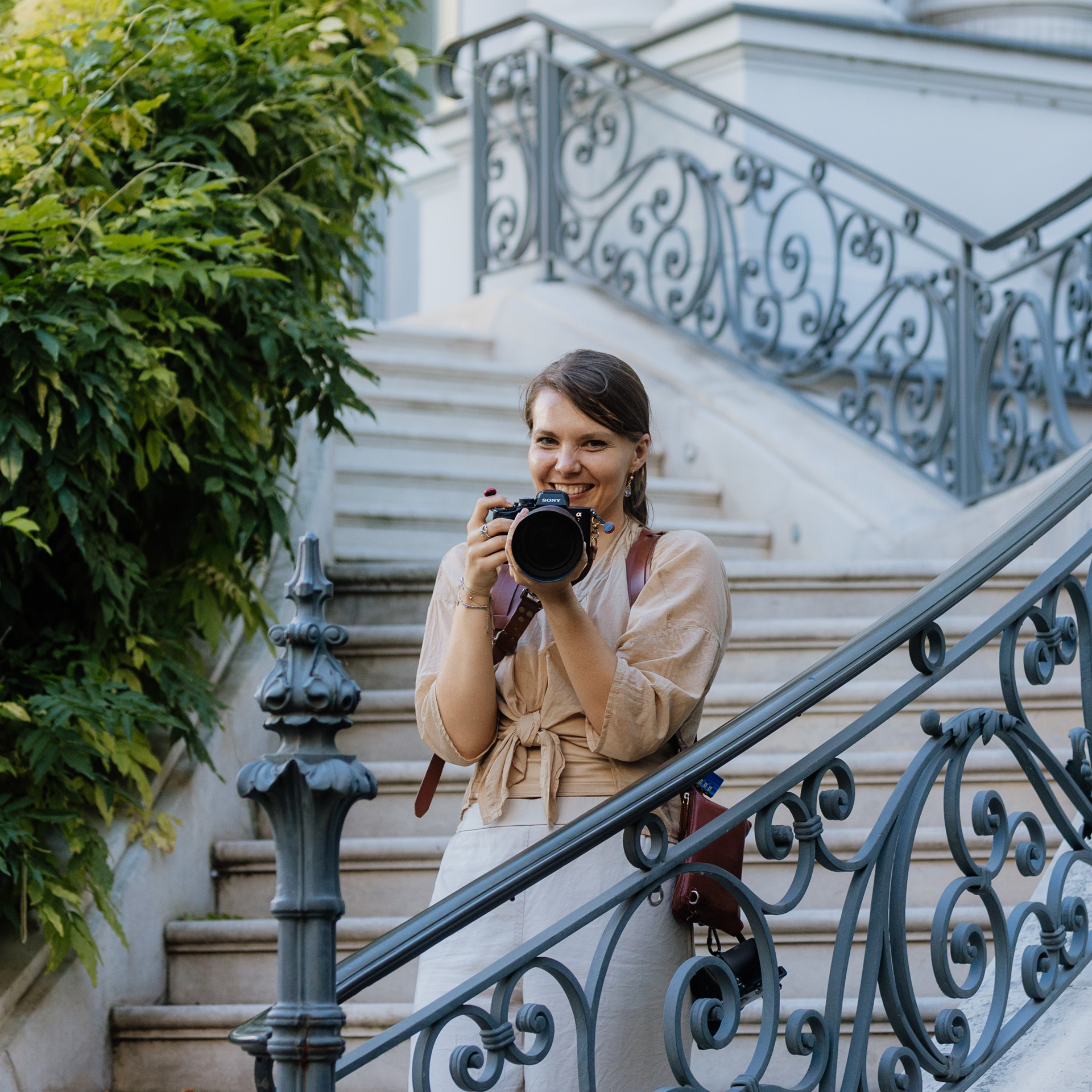 Hochzeitsfotografin steht an einem Stiegenaufgang, mit der Kamera im Anschlag