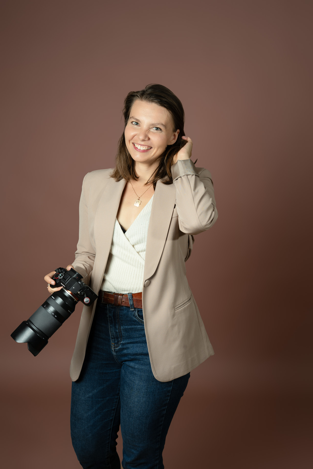Hochzeitsfotografin hält Kamera in die Hand und lächelt