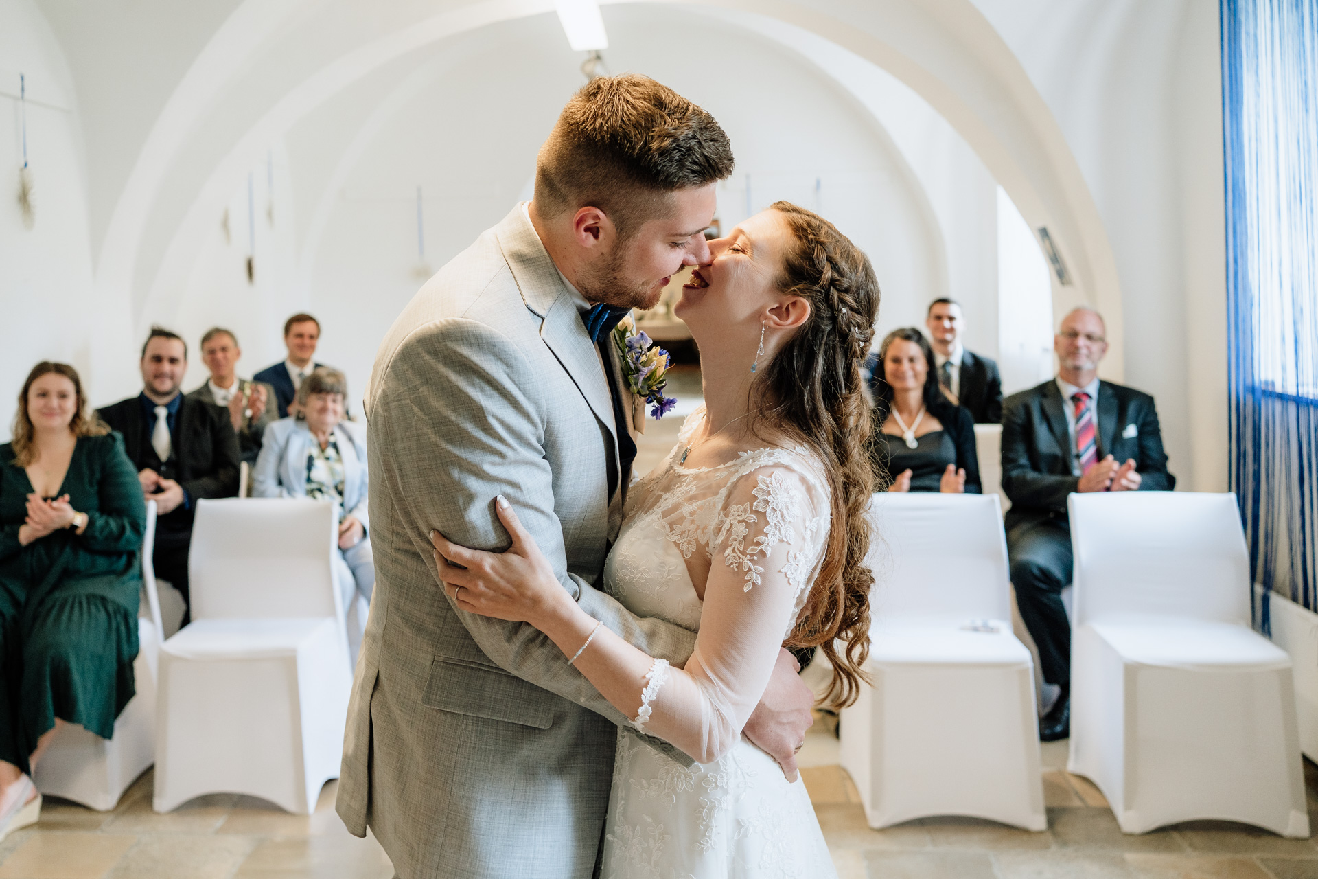 Hochzeitsfoto, Kuss direkt nach der Eheschließung vor der ganzen Familie