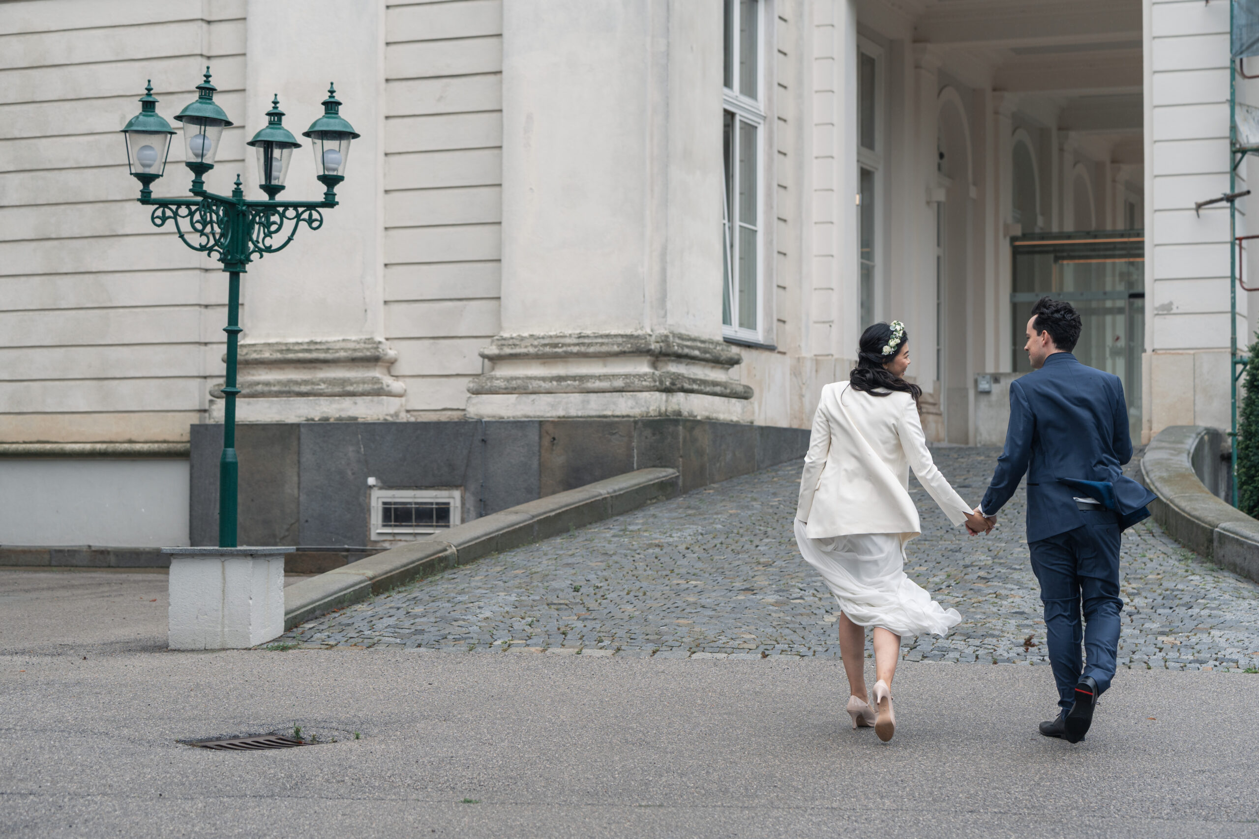 Hochzeitspaar geht händchenhaltend die Rampe des Schlosshotels Wilhelminenberg hinauf